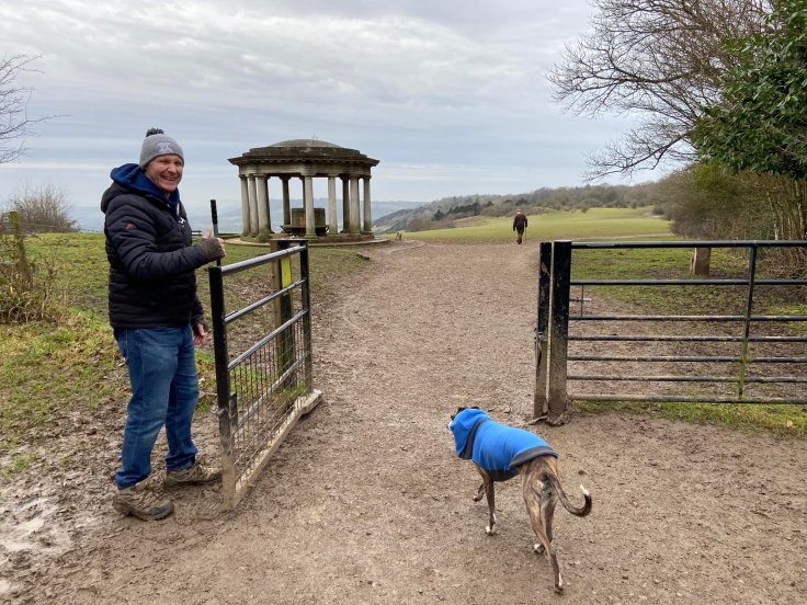 Jim holding open a gate for Jett whippet to pass through with the Inglis Memorial behind and to the left