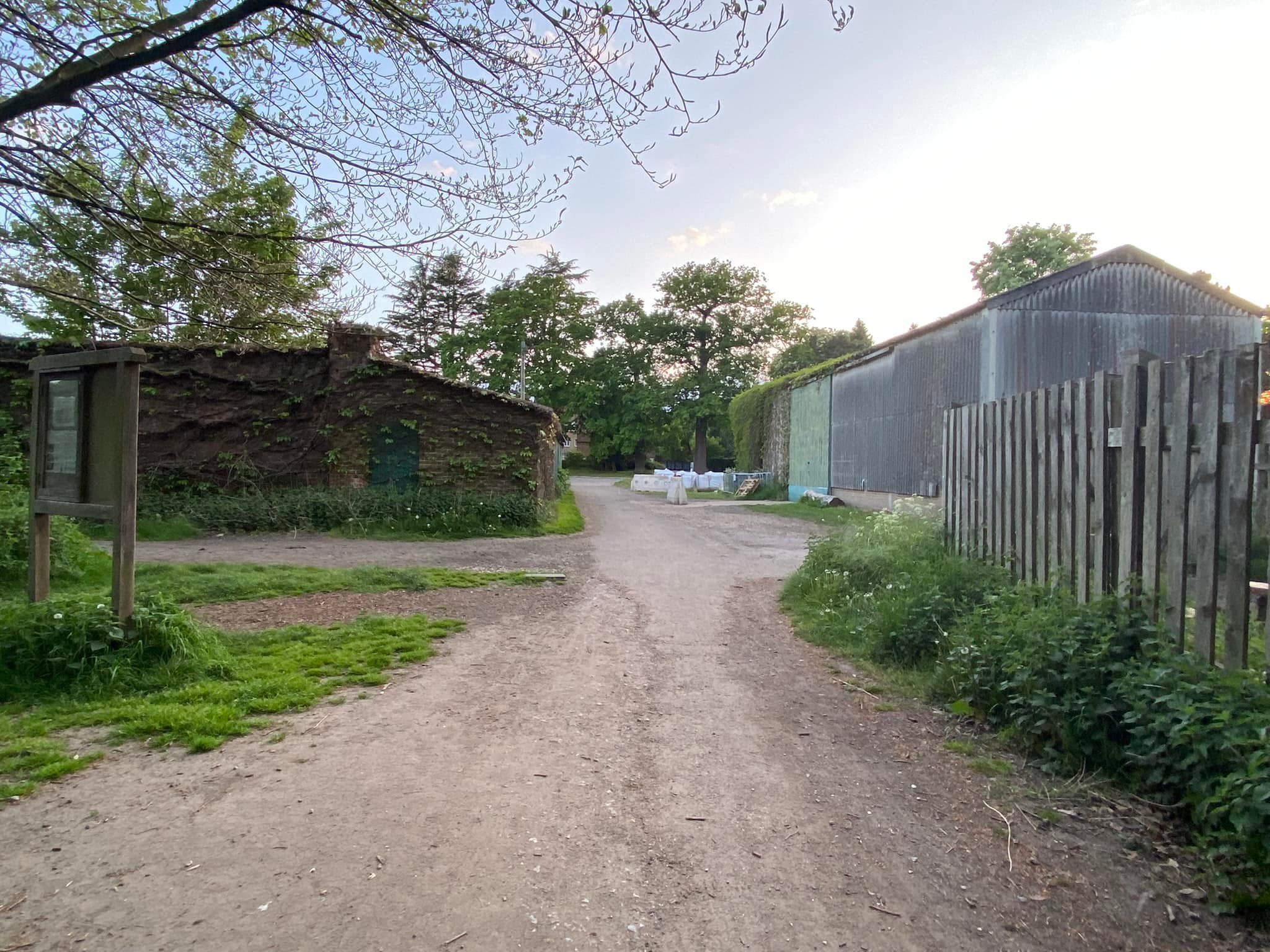 Wooden slatted fence and corrugated iron barn on right